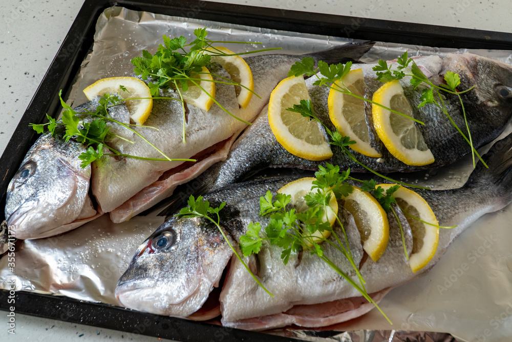 Fresh dorada fish with lemon and parsley on a baking sheet. Fresh seafood