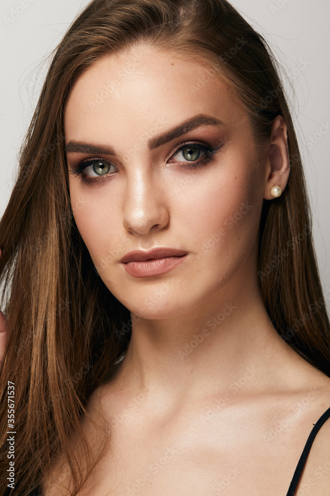 Naklejka premium Beautiful face of young woman with clean fresh skin close up isolated on the grey background. Beauty portrait. Perfect fresh skin. Pure beauty model. Youth and skin care concept