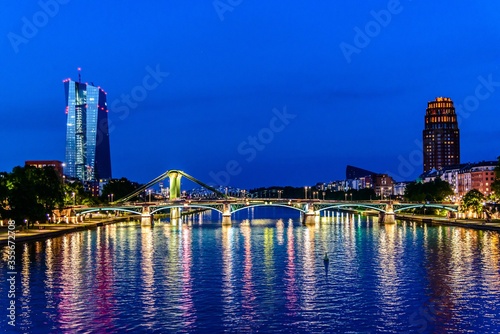 Beautiful view on  Frankfurt am Main, finance center city, downtown skyline cityscape with EZB central bank, bridge during twilight blue hour, sunset, evening, night. Travel inHesse, Germany. © Mikalai