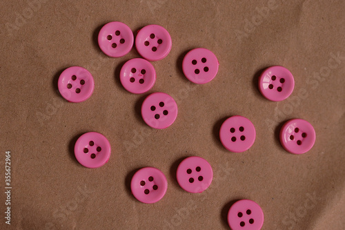 Pink buttons on a brown paper background. Buttons Hardware.