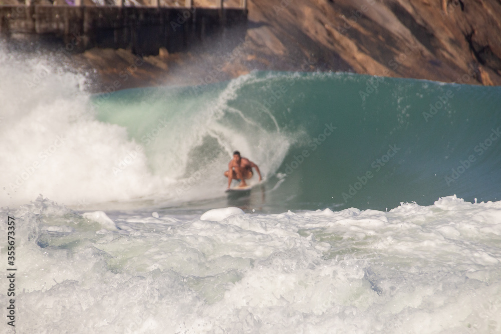 Naklejka premium white foam of a wave at leblon beach with defocused surfer in the background in Rio de Janeiro.