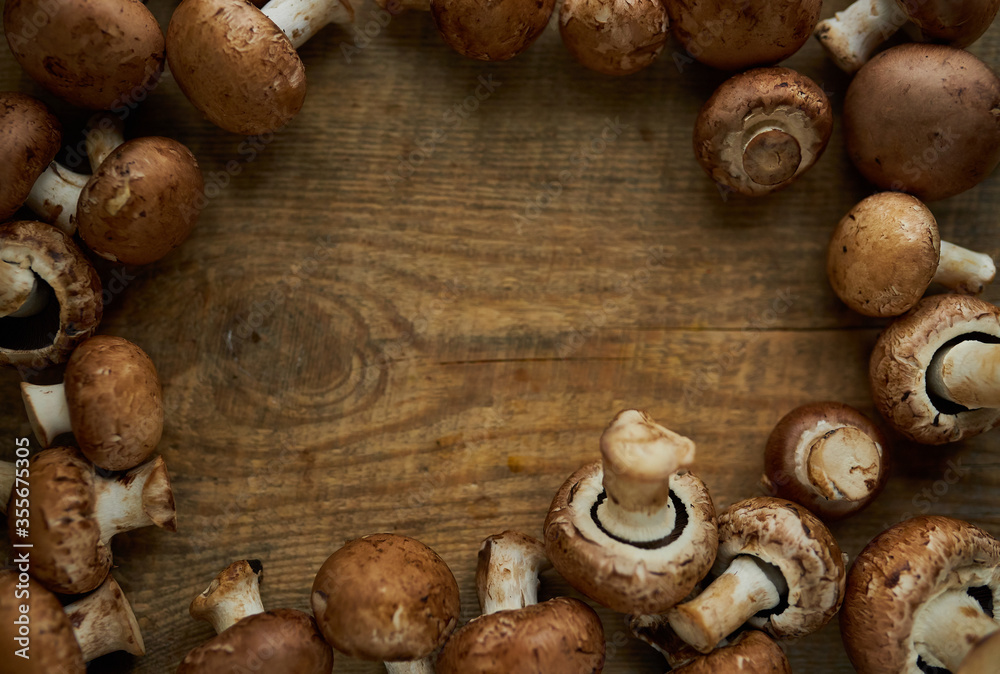 Frame of champignon mushrooms on a wooden background. Champignon mushrooms on a wooden board. Fresh healthy brown mushrooms.