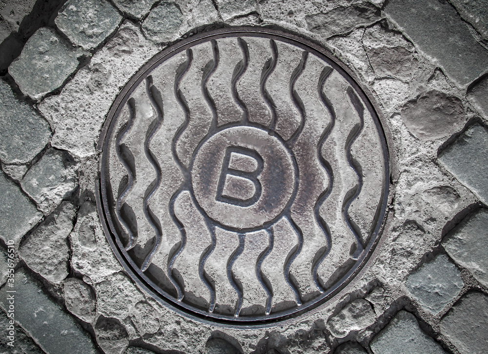 Sewer manhole on a cobblestone road.