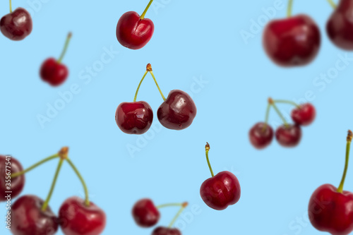 Fresh ripe falling cherries on blue background