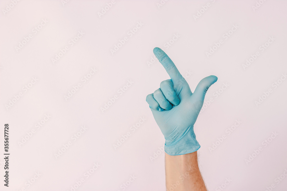 Male hand in latex protective glove point up with index finder on copy space isolated on white background. Closeup man in blue medical glove show with arm to blank copy space. Safe advertisement Male hand in latex protective glove point up with index finder on copy space isolated on white background. Closeup man in blue medical glove show with arm to blank copy space. Safe advertisement