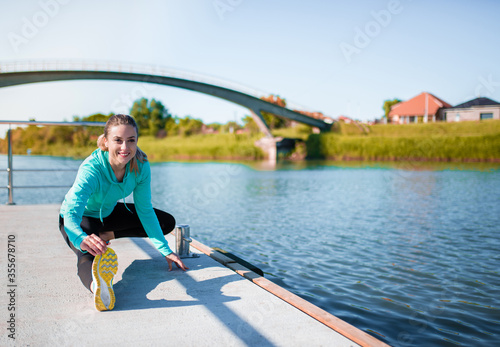 Woman stretching leg muscles outdoors by the river
