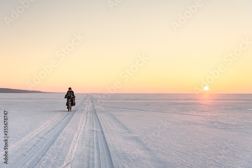 Male bicyclist on Baikal Lake on sunset, Russia
