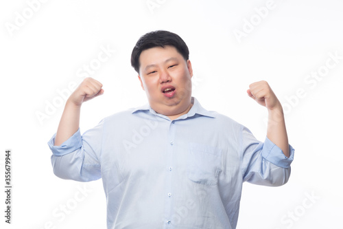 Young Fat Asian business man showing strenght and looking to camera isolated on white background. © Touchr