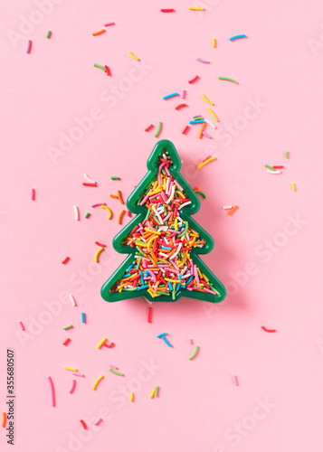 Christmas celebration flat lay with toy christmas tree and sprinkle on pink background photo