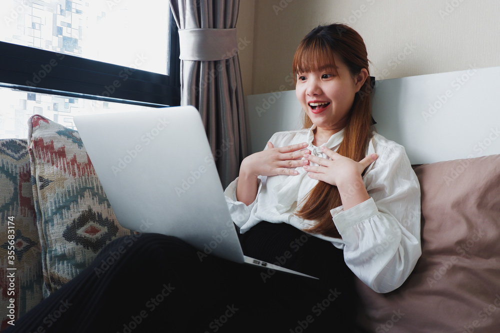 Woman with surprised face while looking at a laptop screen at home.