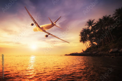 Airplane flying over amazing tropical sunset landscape
