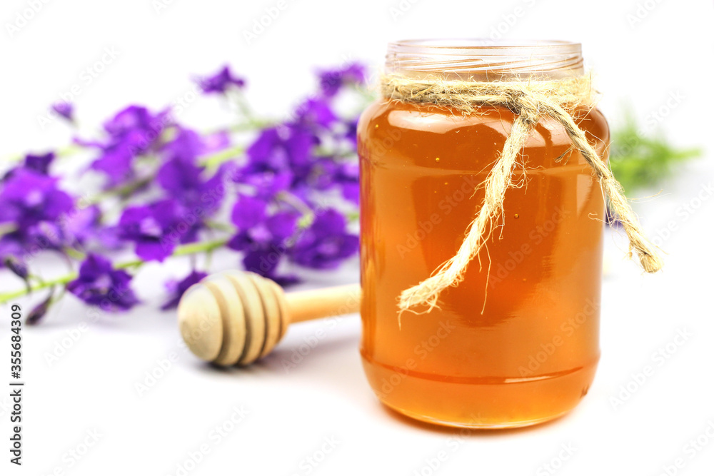 honey dipper, glass jar and wildflowers isolated on white honey dipper, glass jar and wildflowers isolated on white