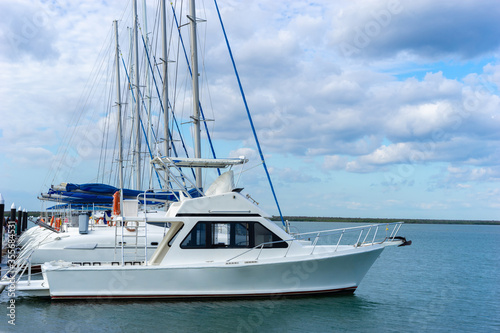 Cuba. Small yachts near the pier. Pier on the seashore. Yachts for tourist excursions. Travels to the Cuba Republic. Swimming in the Caribbean. Boats on blue sky background. Motor yachts