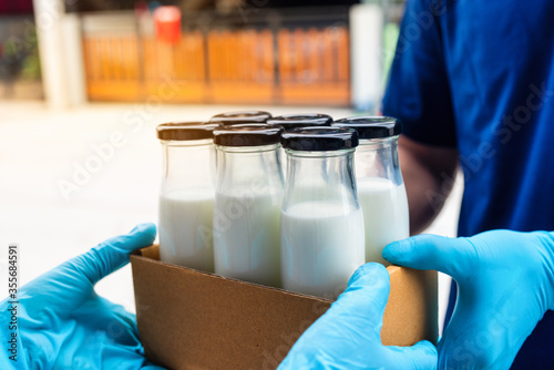 Smart delivery food service man handing box of milk to recipient with woman customer receiving order from courier at home , Woker service milk shopping online. photo