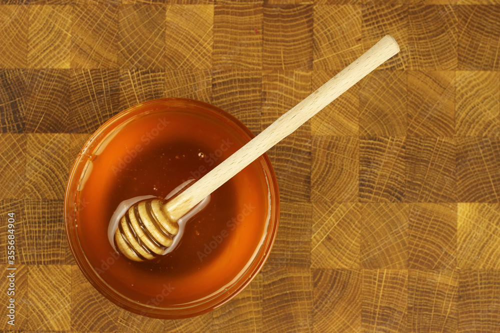 Honey in a bowl with a stick on a wooden Board Honey in a bowl with a stick on a wooden Board