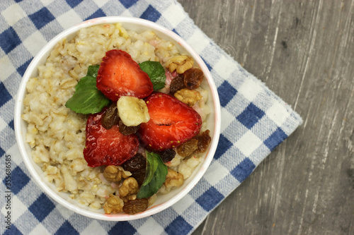 Oatmeal with strawberries, banana and mint on a checkered tablecloth