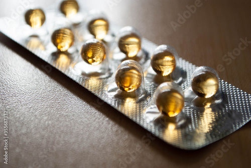 Close-up of yellow pills in foil pack. Macroshooting of Fish oil capsules. Yellow pill capsules. Medicine. Round fish oil pills. Fish Oil Small Softgels. Yellow Softgels photo