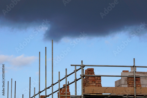 Storm clouds gathering over a building site with scaffolding and bricks piled up