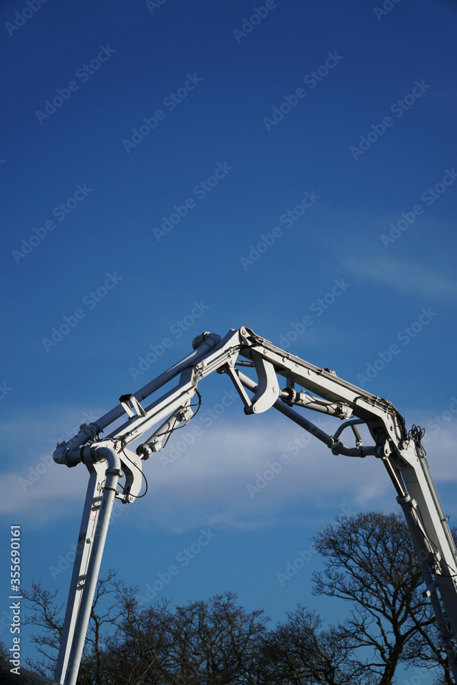 Arm of a concrete pump working on a construction site with a blue sky background Arm of a concrete pump working on a construction site with a blue sky background