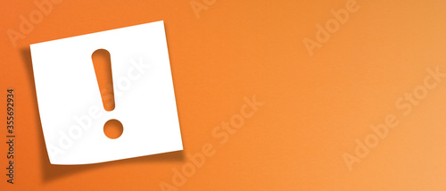 Note paper with exclamation mark on panoramic orange background	

