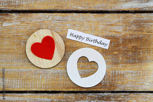 Happy birthday card with two wooden hearts on rustic surface

