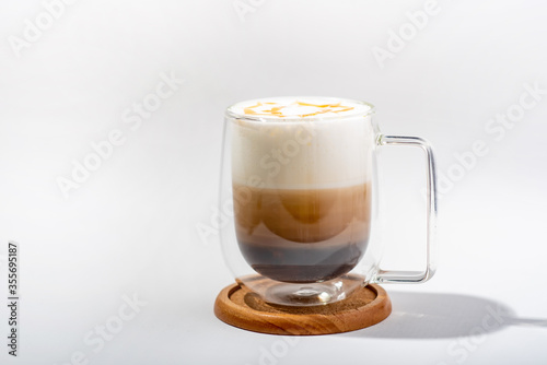 Coffee with Milk froth and caramel in double layer grass on woodplate