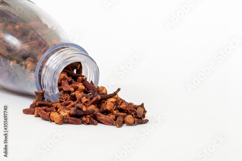 Dry cloves in glass bottle isolated on white background. Closeup macro shot