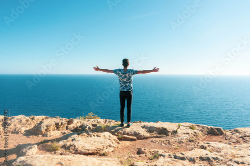 Young man with open arms looking at the sea