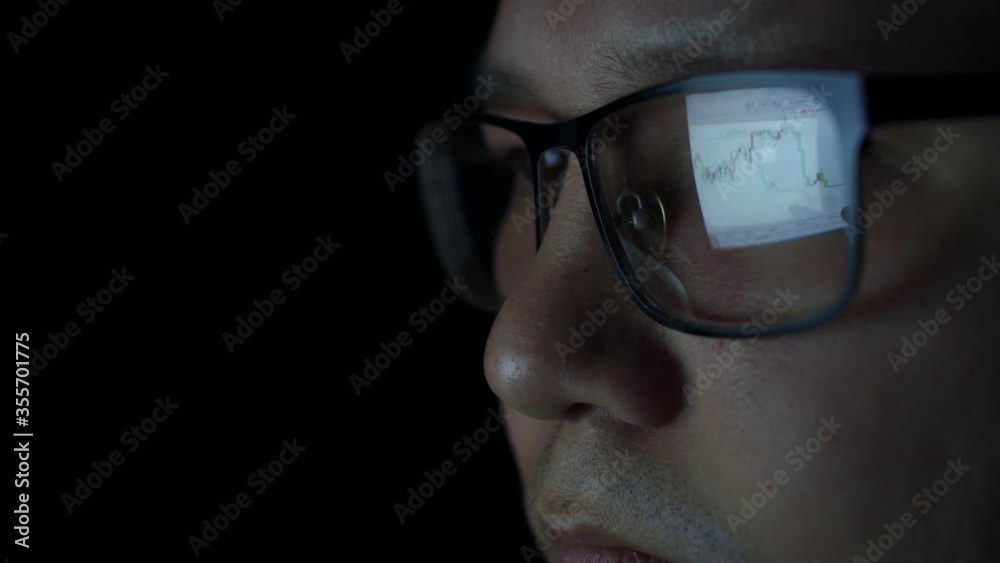 Reflection of the cryptocurrency chart in the businessman's glasses. The Eastern investor follows the cryptocurrency schedule. Reflection of the graph in the glasses of an Asian man Reflection of the cryptocurrency chart in the businessman's glasses. The Eastern investor follows the cryptocurrency schedule. Reflection of the graph in the glasses of an Asian man