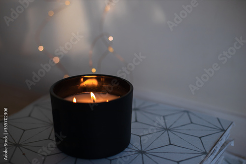 Three burner candle in black glass with bokeh candle lights in the background