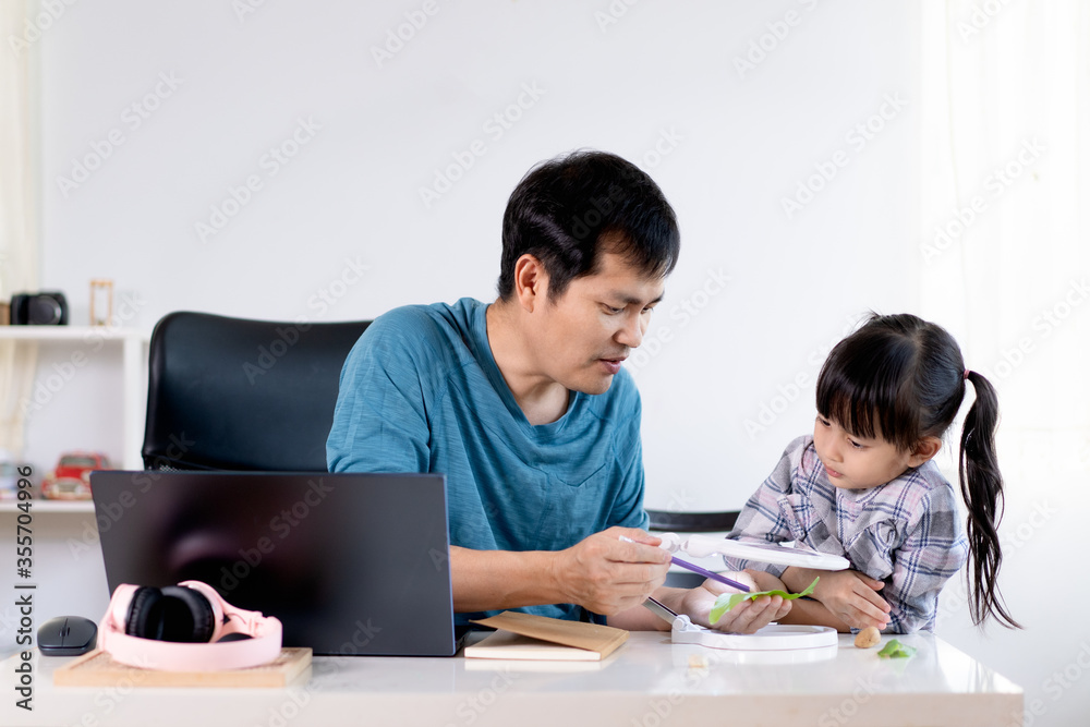 Asian daddy is teaching his daughter to learn about the texture and shape of the leaves through magnifying glass, concept of homeschooling and role of parent to support the child education at home. Asian daddy is teaching his daughter to learn about the texture and shape of the leaves through magnifying glass, concept of homeschooling and role of parent to support the child education at home.