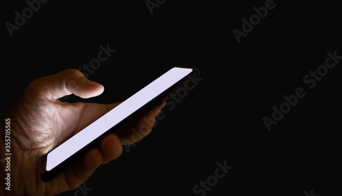 Close-up of hand holding mobile phone on dark background. Concept hacker using mobile phone to steal information online