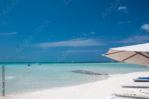 A perfect morning on the beautiful white sand beach with a chaise lounge and umbrella on the shore of the Caribbean sea on Isla Mujeres, Mexico