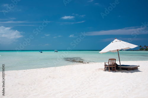 A sunny summer morning on the beautiful white sand beach with a chaise lounge and umbrella on the shore of the Caribbean sea on Isla Mujeres, Mexico © Marco B.