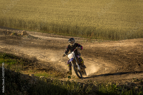 Extreme motocross on motocross track with farming field in background. Dirt track on a sunny late summer day. Motorcycle rider in action