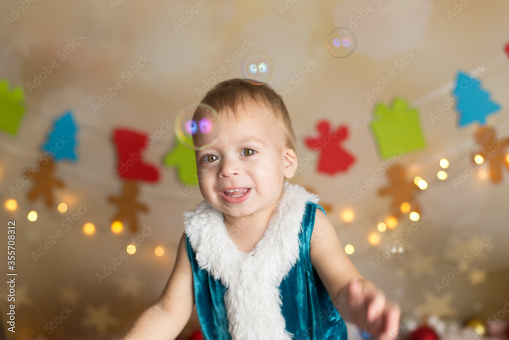 a boy in a Christmas costume catches soap bubbles