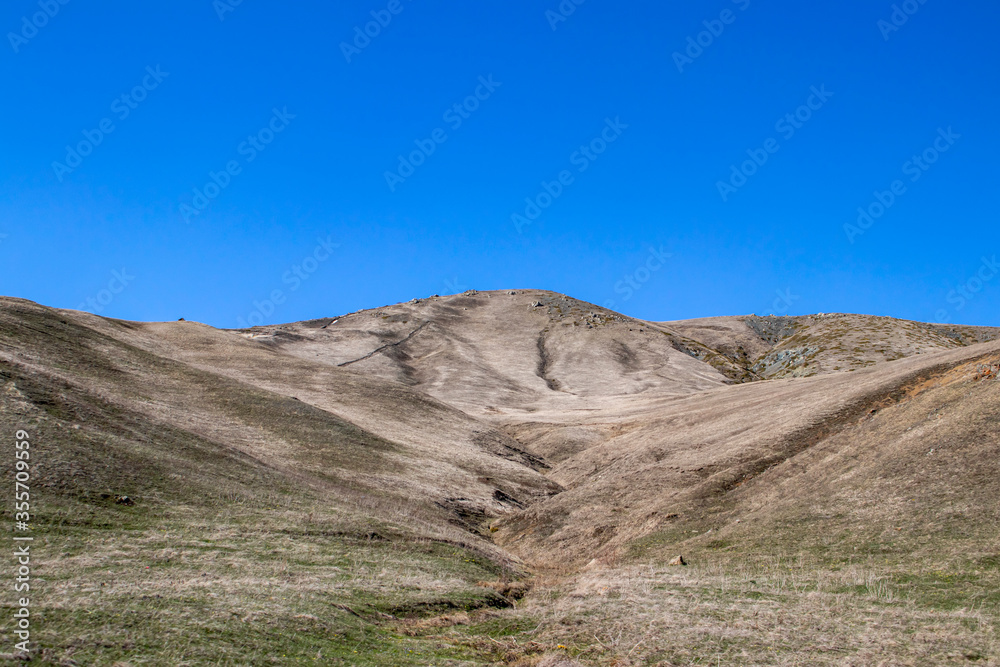 A hill with a dried riverbed. Clear blue sky, mountain landscape.