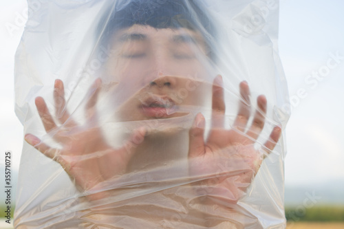 Asian gay man is wearing a plastic bag on his head that has suffocated a concept to stop using plastic and environmental pollution or stops marine and world pollution.And copy space.