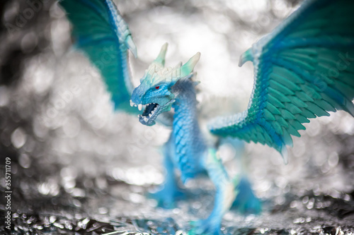 Ice blue dragon toy photo on blur bokeh background, winter cool colors tone