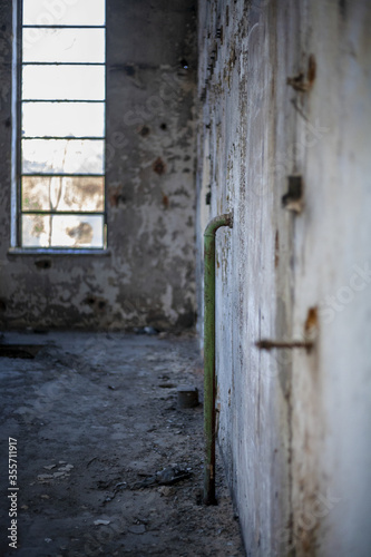 Old empty industrial abandoned factory, dirty interior with big window, moody bright light