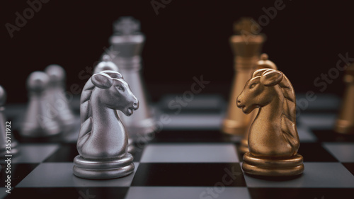 Chess board game staying against full set of chess pieces on black background. Strategy, Planning and Decision business concept