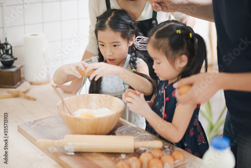 фотографія Young Asian love family are preparing the dough powder, cookies, cake on table in the kitchen which Excited smiling and felling happy