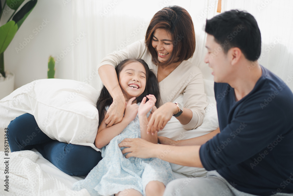Young Asian family love, parent and daughter fun to playing on white bed  which smiling and felling happy at home. father Mother and daughter playing in bed room. Family love stay at home concept