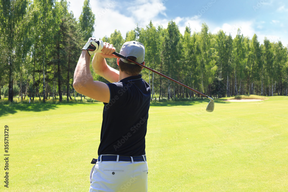 Golfer hits an fairway shot towards the club house. Golfer hits an fairway shot towards the club house.