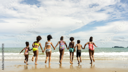 african American,group of children brother or sister hold hands and run together to play in the sea on summer vacation with family or school friend