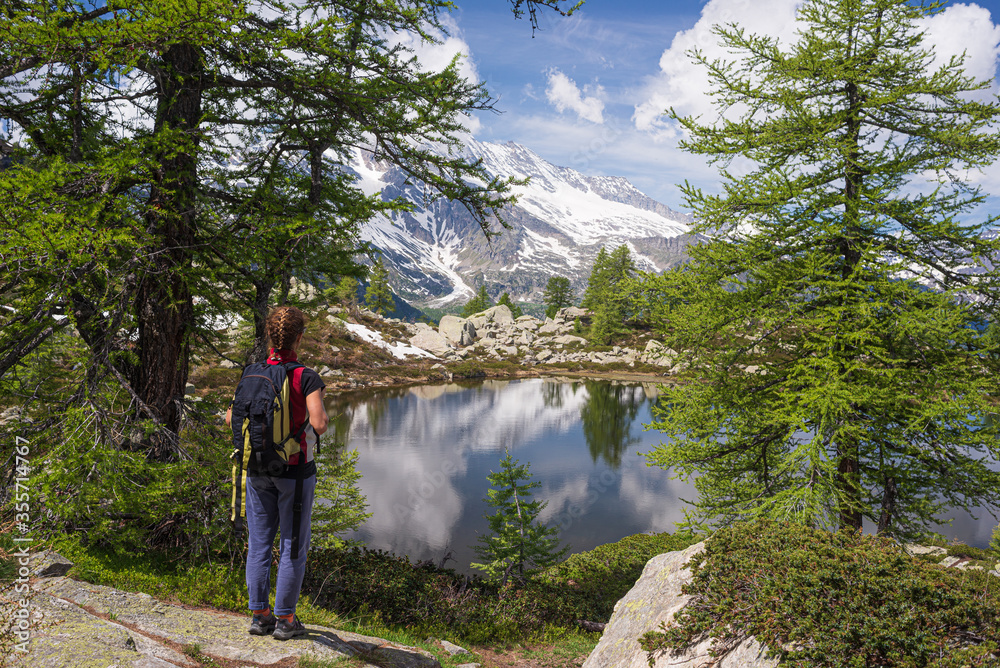 Woman with backpack hiking on mountain. One person looking at view scenic lake alpine landscape summer vacation fitness wellbeing freedom concept