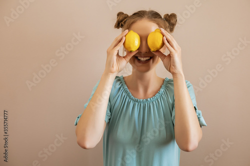 Cute blonde woman is covering her eyes with lemon.Toned image.