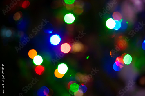 Multi color bokeh background from Christmas, New Year, festive or party light on dark