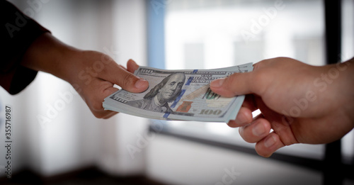 Businessmen give dollars under the table to bribe employees in signing contracts for the purchase of illegal land and real estate, Business fraud and social injustice, corruption and bribery concept.
