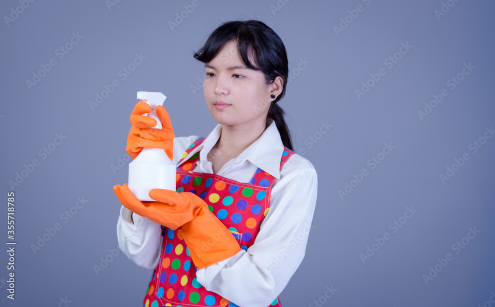 Asian Woman cleaning and polishing the kitchen worktop with a spray detergent, housekeeping and hygiene concept, accessories studio shot isolated on Gray background Asian Woman cleaning and polishing the kitchen worktop with a spray detergent, housekeeping and hygiene concept, accessories studio shot isolated on Gray background